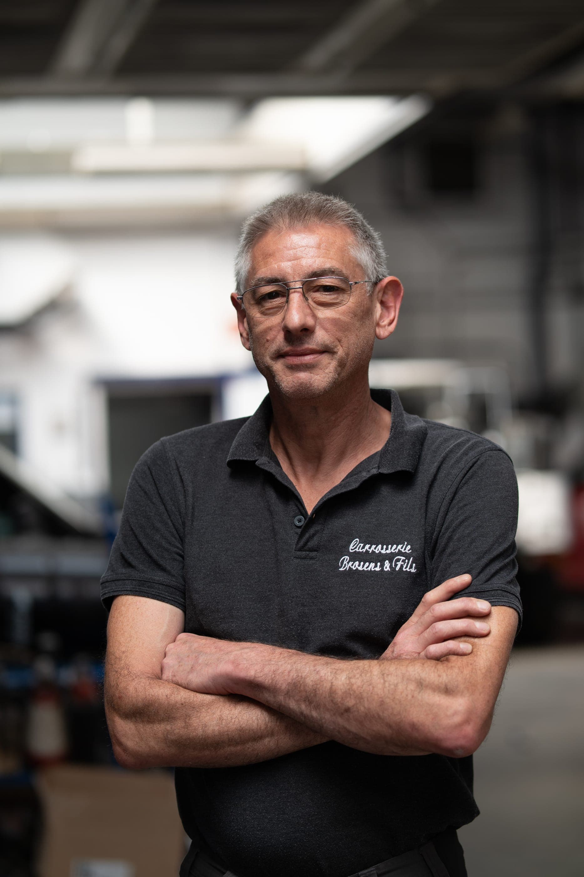 Portrait d’Alain Brosens, gérant actuel, bras croisés dans l’atelier